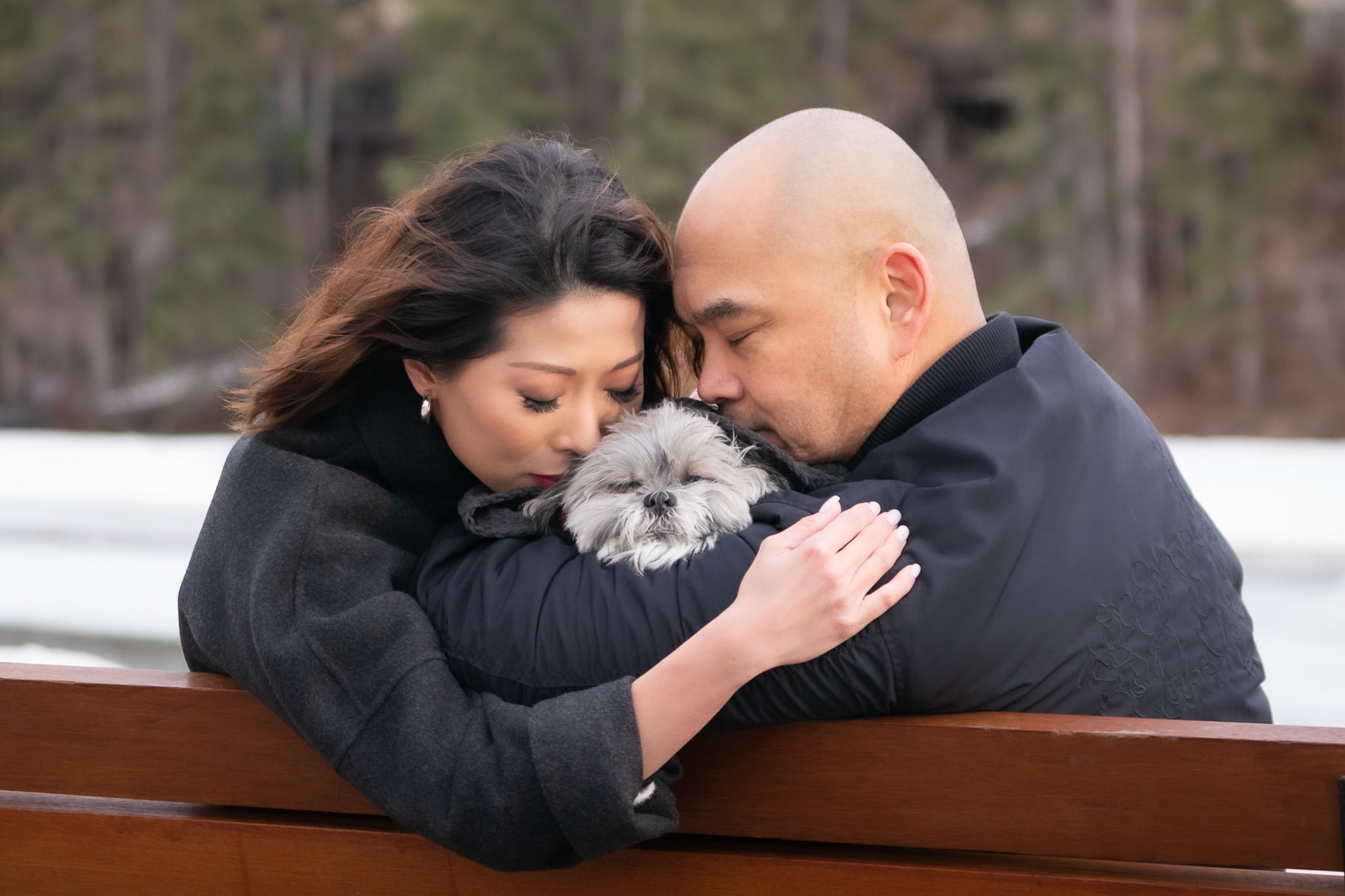 a couple embrace their small dog in love