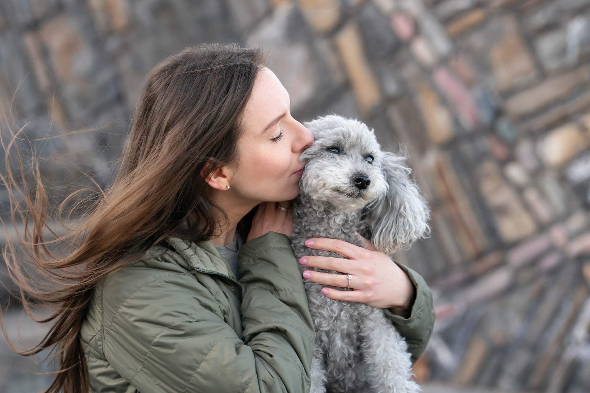 woman kissing her poodle on the cheek