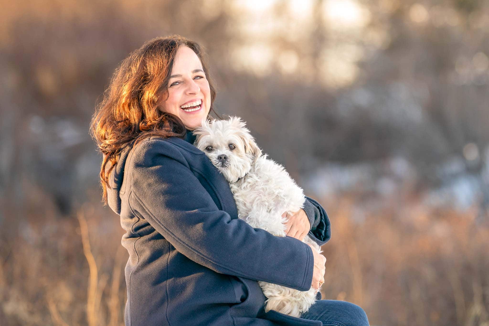 Woman with a big open smile on her face hugging her small elderly dog during a pet photography session in Calgary, Alberta